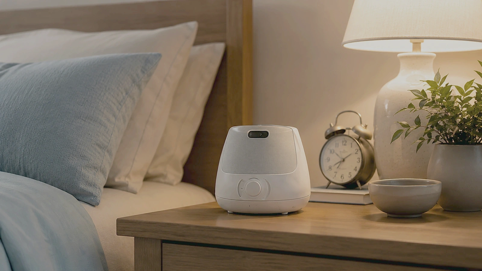 The same white-noise machine and nightstand lit warmly at night